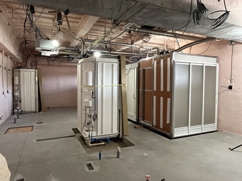 陸上競技場観覧スタンド内に運ばれたシャワー室の設置工事が行われている様子の写真