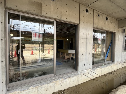 陸上競技場観覧スタンド内に大きなガラス戸が取り付けられた工事の様子の写真