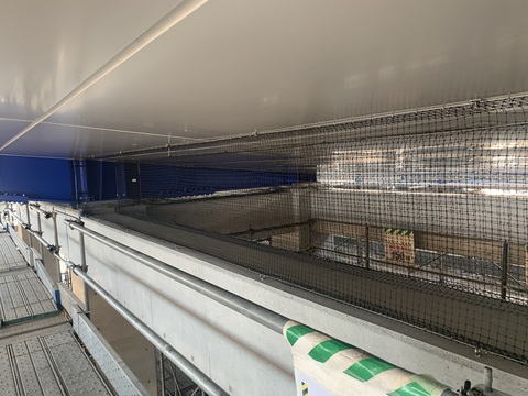 陸上競技場観覧スタンド屋根部分の隙間に黒色の鳥よけネットが取り付けられた様子をアップで撮影した写真