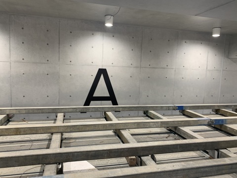 黒色でアルファベットのAの文字が陸上競技場観覧スタンドのコンクリート製の壁に取り付けられた写真