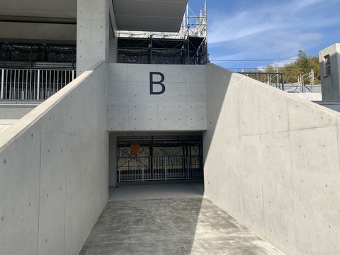 入口上部分に黒色でアルファベットのBの文字が取り付けられた陸上競技場観覧スタンド出入り口ゲートの写真