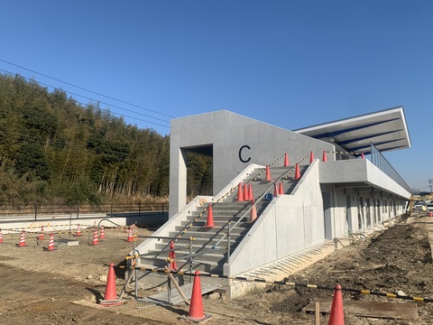 敷地内を囲っていた鋼板塀や周囲の足場が撤去された壁に、アルファベットのCが表示された陸上競技場観覧スタンドのゲート付近の写真