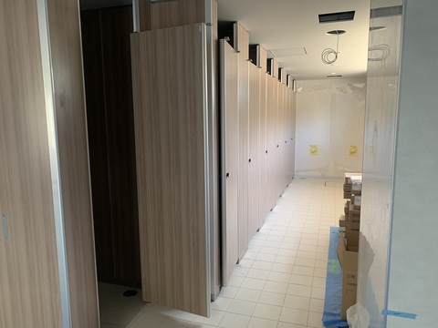 左側に木目調の仕切りや扉が施された7室のトイレの設置工事が行われている様子写真