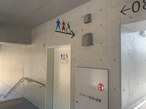 引き戸の中央上部と室内札に、青色と赤色の人型のマークと緑色の車いすのマークのピクトグラム、「バリアフリートイレ」と書かれたサインが取り付けられた写真