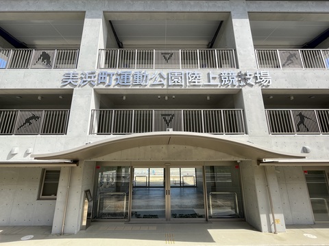 2階と3階の間に「美浜町運動公園陸上競技場」と書かれた看板が設置され、柵にイラストが施されている完成した観覧スタンドの写真