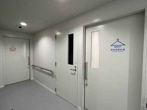 引き戸の中央にハンガーのピクトグラムが描かれ、奥に女性用更衣室、手前に男性用更衣室が設置された出入口の写真
