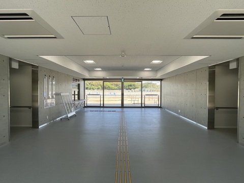 出入り口に大きなガラス戸が設置され、左側に受付、通路中央部分の左右に通路が設けられている観覧スタンド入り口の写真