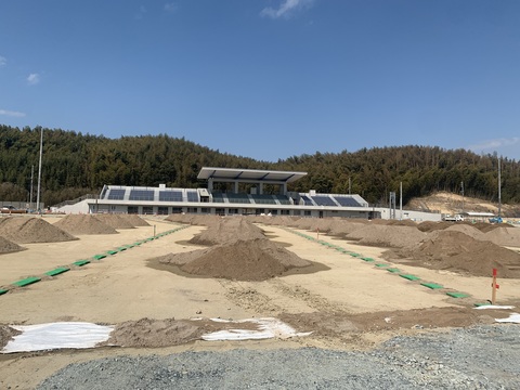 観客席の手前のフィールド部分に、山積みされた砂が列をなして並んで置かれている写真