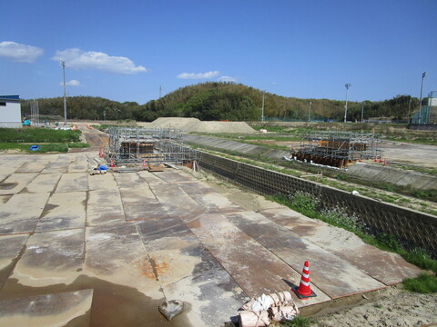 運動公園へ渡る山王川の両端に、足場で囲まれた人道橋の橋台部分の工事の様子を撮影した写真
