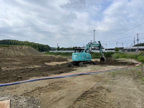 交流広場の工事予定地で、水色のボディのショベルカーが沈砂池の埋戻工事を行っている様子の写真