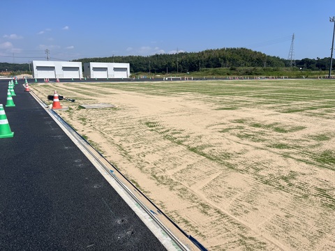 器具庫側の広大なフィールド部分で人工芝の上から砂を敷設した工事の様子写真
