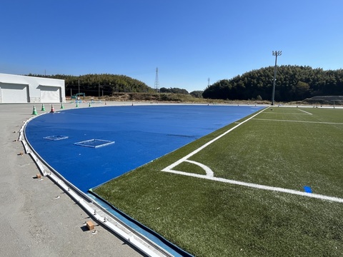 サッカーコートの外左側の半円形のフィールド部分に、青色で舗装工事が行われた写真