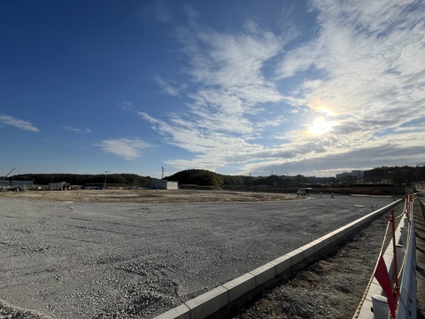 地面を砕石や砂利で敷きならされた交流広場の工事予定地で、路盤工事が行われている様子の写真