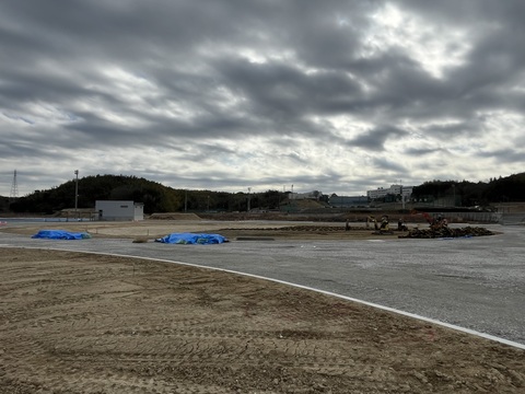 上空に黒い雲がたちこめている交流広場の建設予定地で、芝敷設工事が行われている様子の写真