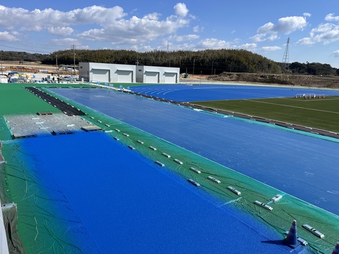 フィールド部分に鮮やかな青色で舗装された工事の様子を撮影した写真