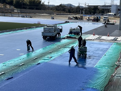 ヘルメットを被った5名の作業員が舗装工事を行っている様子をアップで撮影した写真