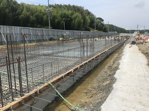 地上から2メートルくらい窪んだ建設予定地の陸上競技場観覧スタンド1階床部分で行われているコンクリートの打設工事の様子写真