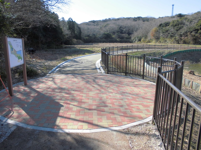 右側にフェンスが設置され、歩道の一部が丸い形をして、ピンクと黄色のタイルがちりばめられた遊歩道の写真