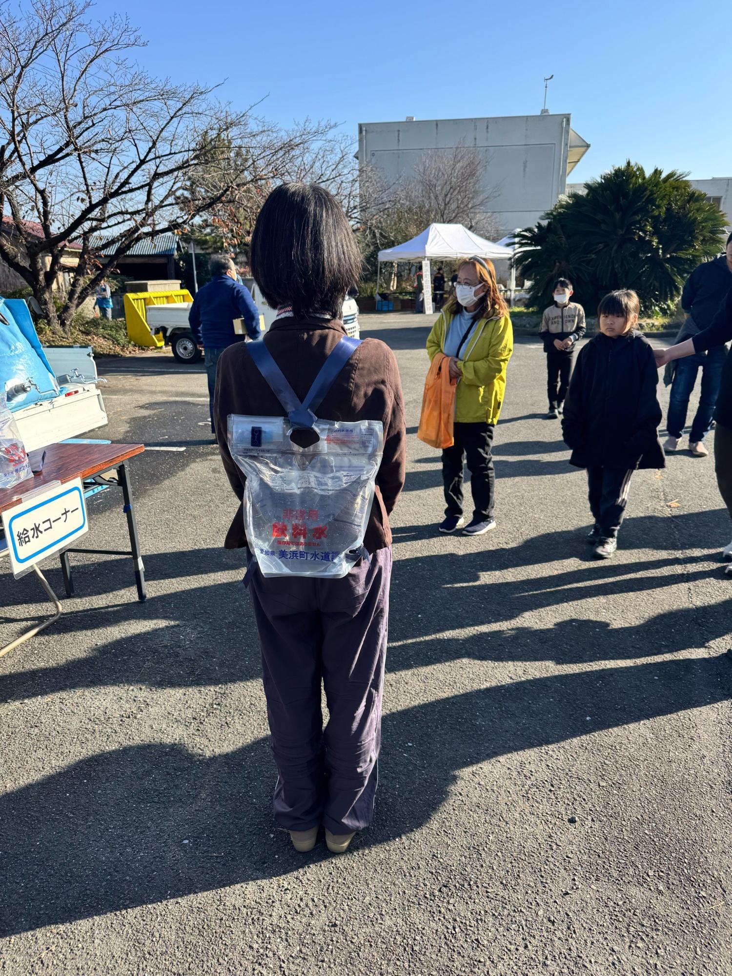 女性が背負い式給水袋を背負っている写真