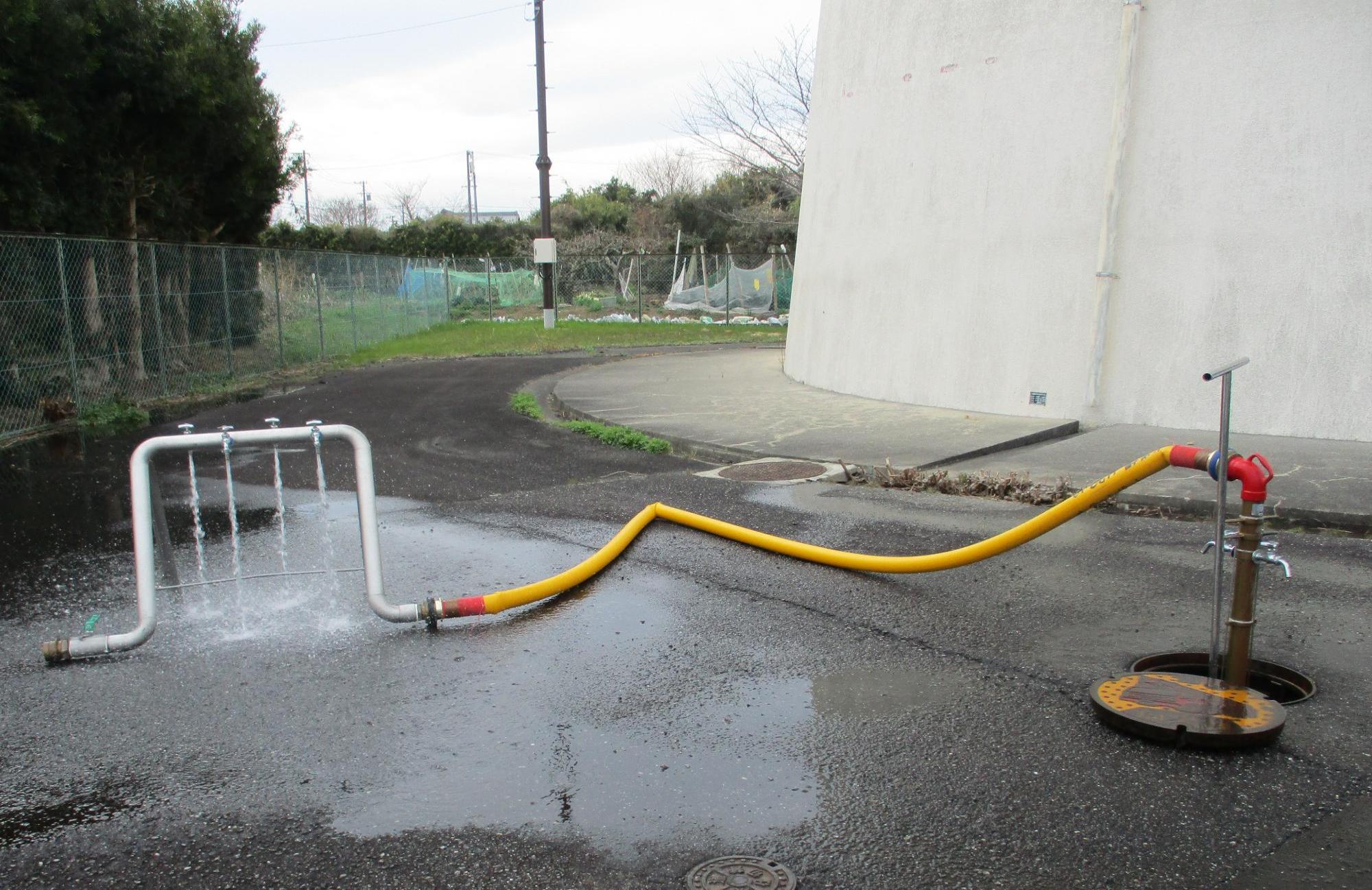 消火栓に、専用器具、飲料用ホース、4つ蛇口が付いた仮設給水栓を接続した写真