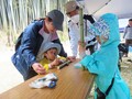 長机の上で、男性とお母さんが見守る中で男の子が作業をしている様子の写真