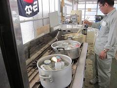 イチゴジャムを詰める瓶を大きな鍋で煮沸消毒している男性の写真