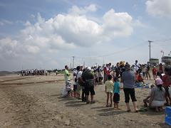砂浜で二手に分かれて大きな輪を作って集まっている沢山の参加者達の写真