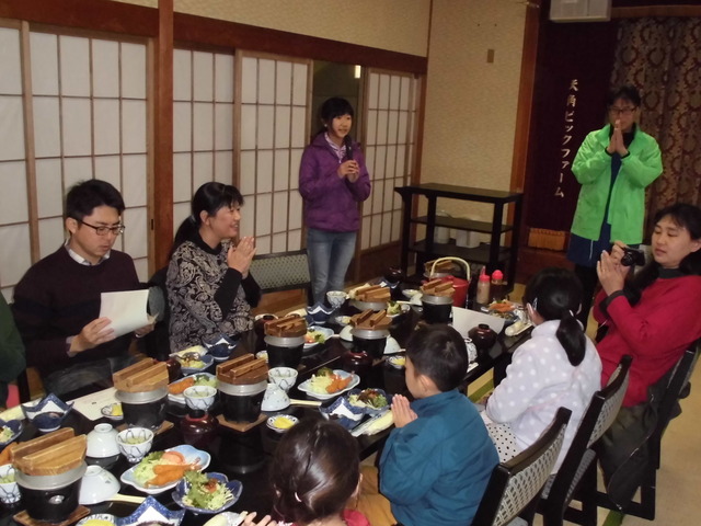 沢山の料理が並べられたテーブルに参加者たちが向かい合って座っている、老舗旅館紅葉屋での海音貝（うんね）釜飯ランチの昼食時の様子写真