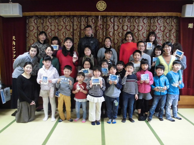 完成した貝殻フォトフレームを手に持ち笑顔で写っている参加者たちの集合写真