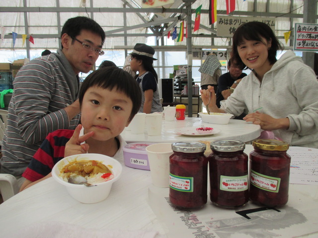 完成した瓶詰めの手作りジャムとカレーライスを食べている親子の写真