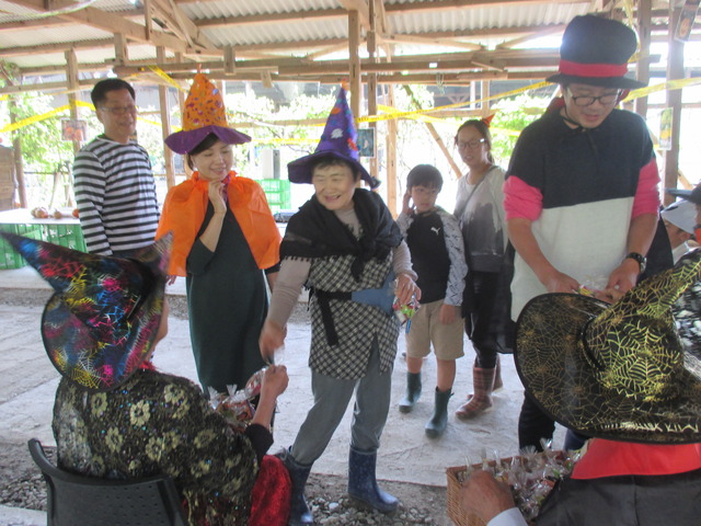 椅子に座っている人達からお菓子をもらおうとハロウィンの衣装を着た参加者たちが並んでいる写真
