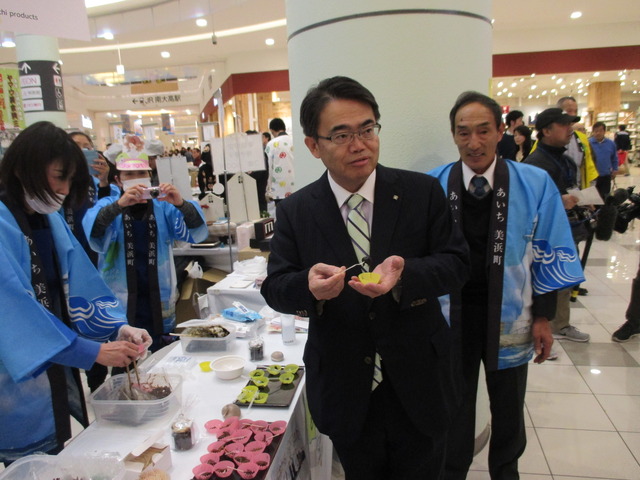 即売会に来場した大村秀章愛知県知事が試食品を手にしている写真