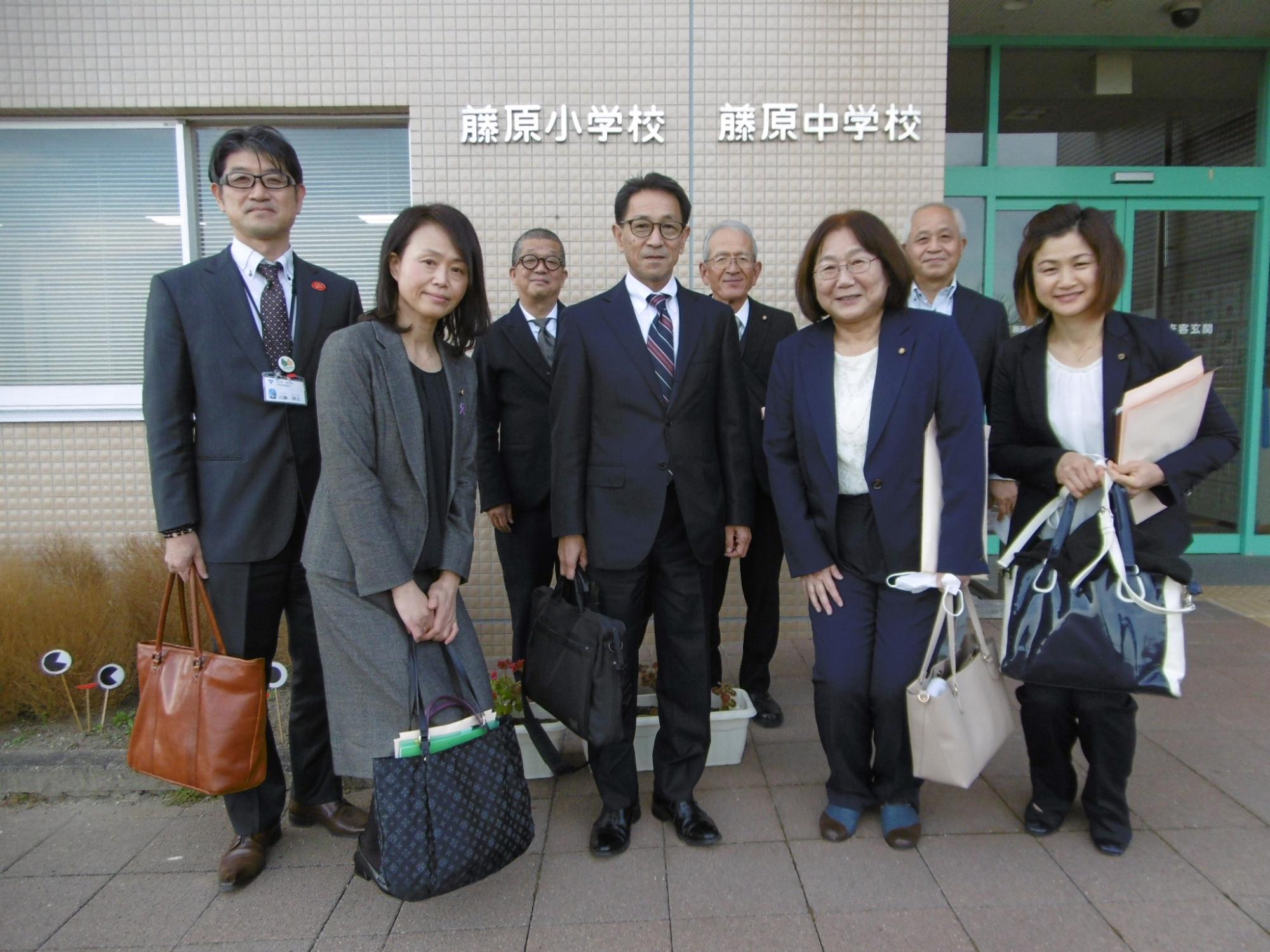 藤原小学校・藤原中学校と書かれた建物の前で撮影された女性3名男性5名の関係者の方々の写真