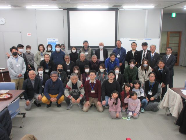 会場の正面に集まった関係者たちが、横4列ほどに並んで一緒に記念撮影をしている写真