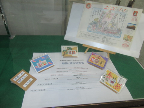 新語・流行語大賞の受賞作品一覧や、カラフルにデザインされたお年玉切手シートが展示されている写真