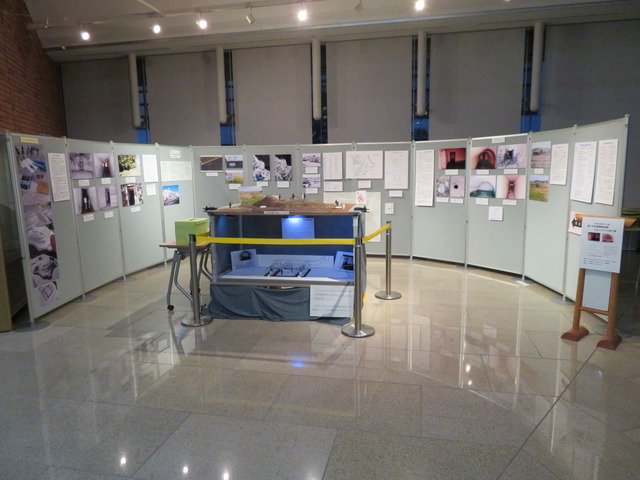カーブをかけて並べられたパーテーションに展示されたボードや、展示スペースの中心に設置されたジオラマの展示物を一緒に撮った写真