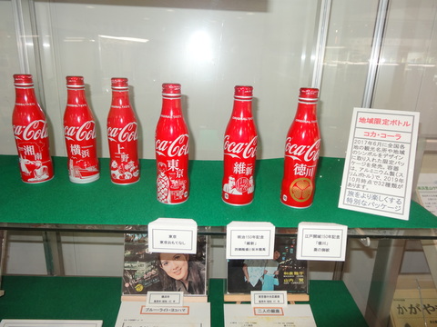地域のシンボルがデザインされた6種類のコカ・コーラのボトルが展示されている写真