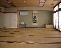 障子から明るい光がもれている畳の部屋で壁に掛け軸が飾られている和室の写真
