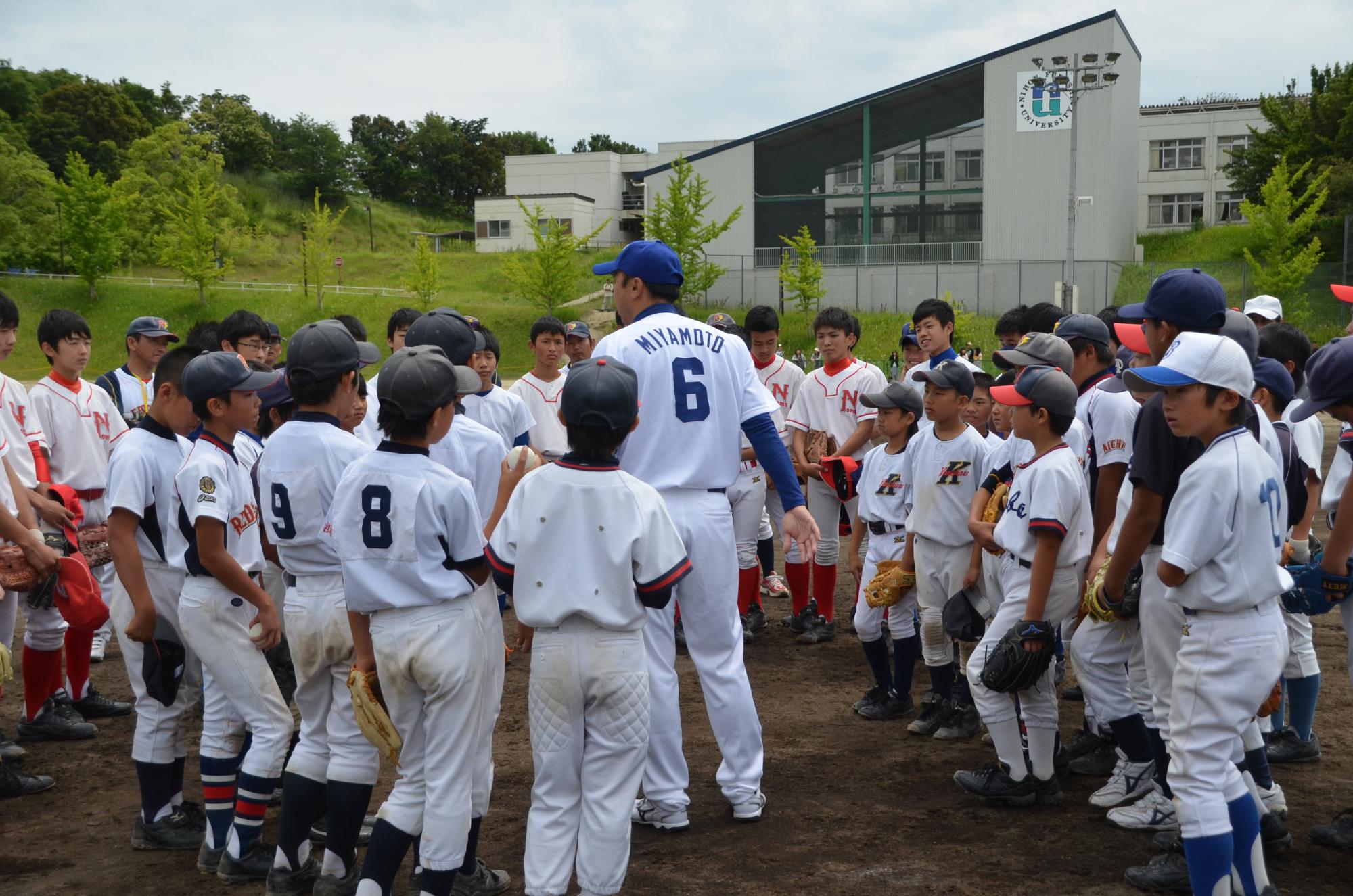 宮本選手の指導をたくさんのユニフォーム姿の子供達が集まり聞いている様子を写した写真