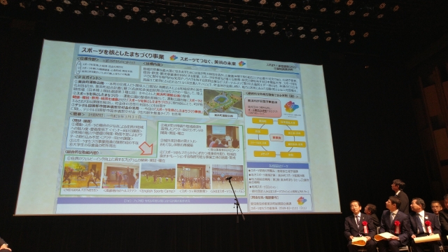 「スポーツを核としたまちづくり事業 スポーツでつなぐ、美浜の未来」の資料を大きくスクリーンに映し出した写真